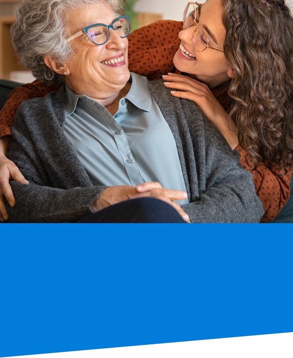 elderly woman and her adult daughter hugger her from behind